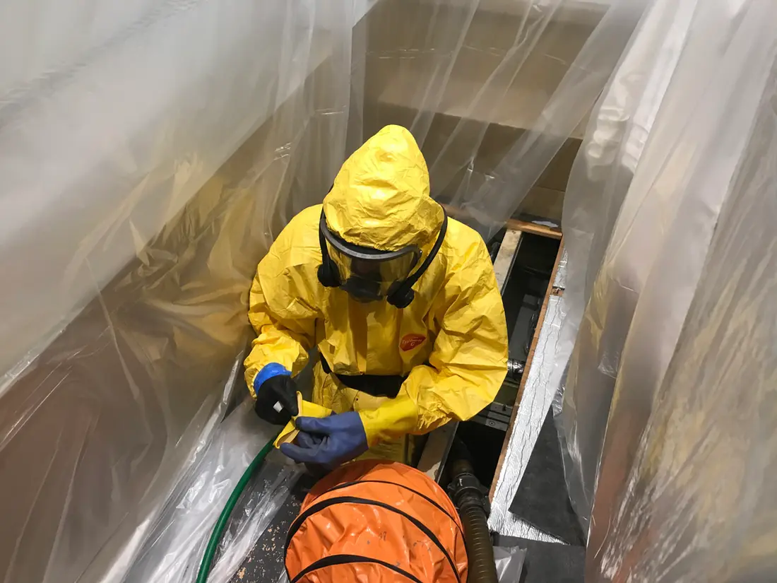 Technicien en combinaison et masque dans un réservoir